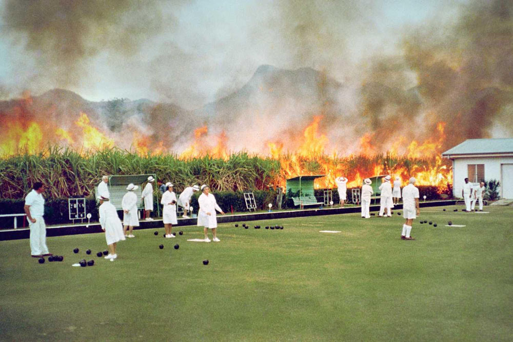 Mossman bowlers play on regardless of cane burning behind them in this historic photo. Picture: Supplied