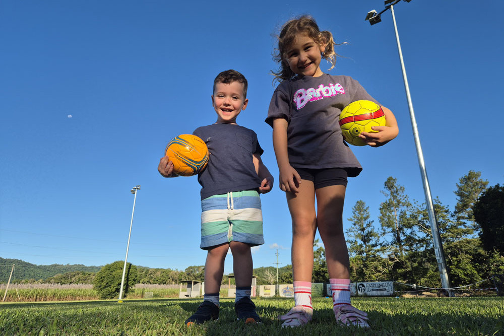 Douglas United Football Club “Squirts” Noah and Tilly in front of the club’s new lights. Picture: Supplied