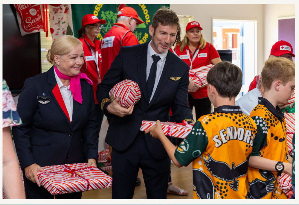 Captain Peter Robinson and flight attendant Bridgette Harrison hand out the gifts at Mossman State School. Pictures: Qantas Australia